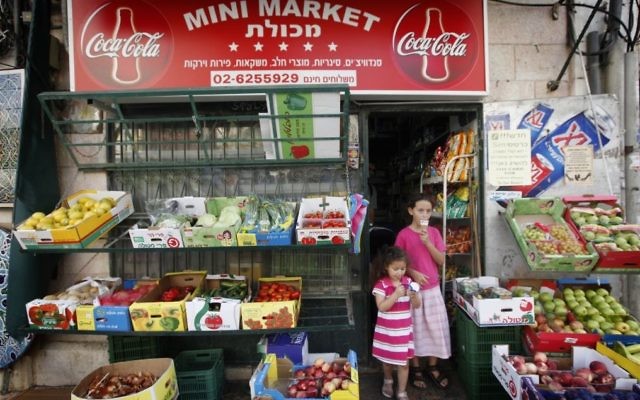 Deux jeunes filles mangent de la crème glacée devant une épicerie à Jérusalem, le 2 août 2010 (Crédit : Miriam Alster / Flash90)