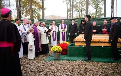L'archevêque de Maribor, Alojzij Cvikl (4° à gauche), bénit un cercueil pendant une cérémonie marquant le début des funérailles de quelques 800 personnes assassinées par les forces communistes après la Seconde Guerre mondiale au parc mémoriel de Dobrava, à Maribor, en Slovénie, le 27 octobre 2016. (Crédit : AFP/Jure Makovec)