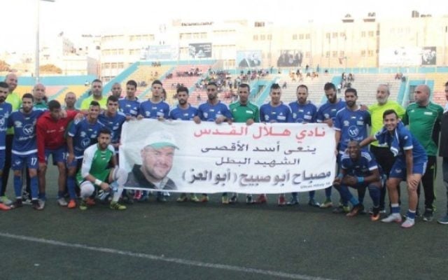 L'équipe de football palestinienne Hilal al-Quds pose avec une bannière qui rend hommage au terroriste palestinien Mesbah Abu Sabih, qui a tué deux Israéliens lors d'une fusillade à Jérusalem, le 9 octobre 2016. (Crédit : Facebook) L'équipe de football palestinienne Hilal al-Quds pose avec une bannière qui rend hommage au terroriste palestinien Mesbah Abu Sabih, qui a tué deux Israéliens lors d'une fusillade à Jérusalem, le 9 octobre 2016. (Crédit : Facebook)