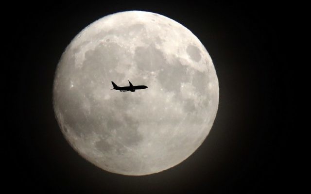 Un avion de ligne passe devant la Lune à son approche de l'aéroport d'Heathrow, à l'ouest de Londres, le 13 novembre 2016. (Crédit : AFP/Adrian Dennis)