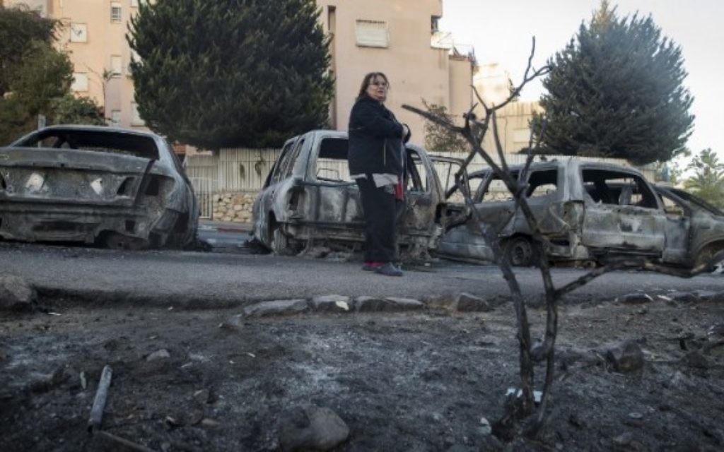 Une femme passe devant les voitures brûlées par les feux de forêt du 25 novembre 2016. (Crédits : AFP)