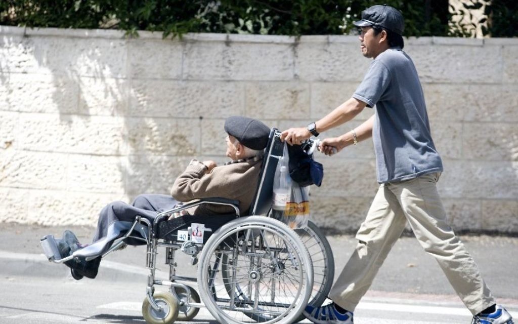 Un aide soignant philippin poussant un Israélien âgé en chaise roulante, le 22 avril 2009. (Crédit : Abir Sultan/Flash90)