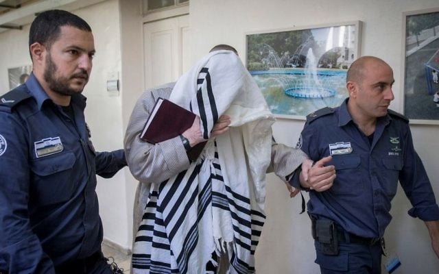 Rabbi Eliezer Berland se couvrant de son talit au tribunal de Jérusalem où il a été condamné pour actes indécents et voies de fait, le 22 novembre 2016. (Crédit : Yonatan Sindel / Flash90)