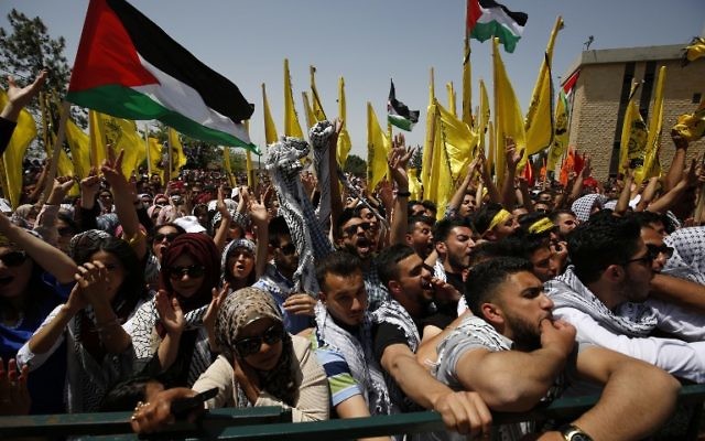 Les étudiants palestiniens qui soutiennent le mouvement du Fatah agitent le drapeau national et celui du mouvement durant un rassemblement en vue d'une campagne électorale pour le conseil étudiant à la  Birzeit University, à proximité de la ville cisjordanienne de Ramallah le 26 avril 2016 (Crédit :  / AFP PHOTO / ABBAS MOMANI