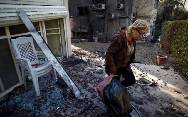 Une Israélienne récupère des affaires d'une maison calcinée, touchée par les feux de forêt du nord de Haïfa, le 25 novembre 2016. (Crédit : Gili Yaari/Flash90) Une Israélienne récupère des affaires d'une maison calcinée, touchée par les feux de forêt du nord de Haïfa, le 25 novembre 2016. (Crédit : Gili Yaari/Flash90)