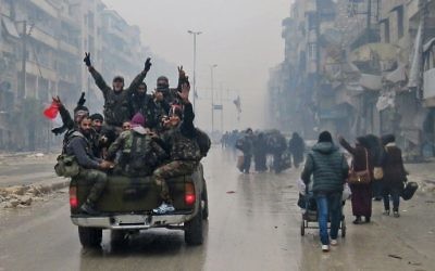 Des combattants pro-régime syrien et des habitants fuyant les violences dans le quartier Bustan al-Qasr d'Alep, le 13 décembre 2016. (Crédit : AFP/Stringer)