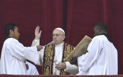 Le pape Francis (C) bénit depuis le balcon de la basilique Saint-Pierre lors du traditionnel message de Noël "Urbi et Orbi" à la ville et au monde, le 25 décembre 2016 à la place Saint-Pierre au Vatican. (Crédit : AFP / ANDREAS SOLARO)
