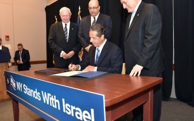 Le gouverneur Andrew M. Cuomo signe un ordre exécutif qui impose le désinvestissement des fonds publiques des entreprises qui soutiennent l mouvement BDS, au Harvard Club de New York City, le 5 juin 2016. (Crédit : Kevin P. Coughlin/Office of Governor Andrew M. Cuomo)