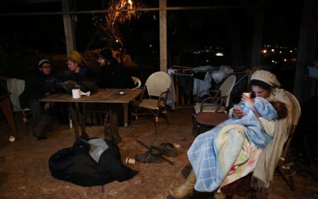 Des familles assises devant une maison de l'avant-poste d'Amona, en Cisjordanie, le 17 décembre 2016. (Crédit : Miriam Alster/Flash90)