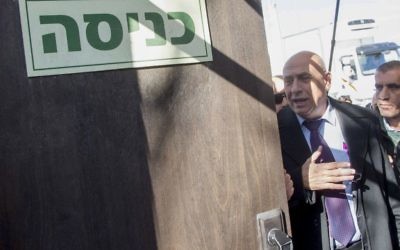 Le membre de la Knesset de la Liste (Arabe) Unie  Basel Ghattas,au centre, arrive aux bureaux de l'unité policière d'enquête Lahav 433 à Lod, le 20 décembre 2016 (Crédit : Roy Alima/Flash90)