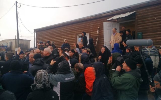Yoav Galant, ministre du Logement, quitte Amona entouré par des manifestants qui se sont rassemblés dans l'avant-poste de Cisjordanie dans l'espoir 'empêcher son évacuation, le 18 décembre 2016. (Crédit : Judah Ari Gross/Times of Israel)