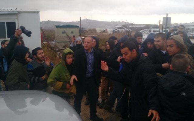 Yoav Galant, ministre du Logement, quitte Amona entouré par des manifestants qui se sont rassemblés dans l'avant-poste de Cisjordanie dans l'espoir 'empêcher son évacuation, le 18 décembre 2016. (Crédit : Judah Ari Gross/Times of Israel)