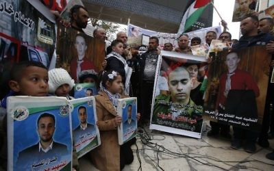 Des Palestiniens rassemblées dans les rues de Hébron, en Cisjordanie, pendant le verdict du soldat israélien Elor Azaria (portrait, au centre) qui a tué Abdel Fattah al-Sharif (portrait, à gauche), le 4 janvier 2017. (Crédit : Hazem Bader/AFP)