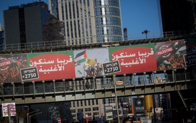 Campagne des "Commandants pour la sécurité d'Israël" présentant une affiche portant le drapeau palestinien et le message "un état pour deux peuples - Palestine", au-dessus de l'autoroute Ayalon, dans le centre de Tel Aviv, le 15 janvier 2017. (Crédit : Miriam Alster/Flash90)
