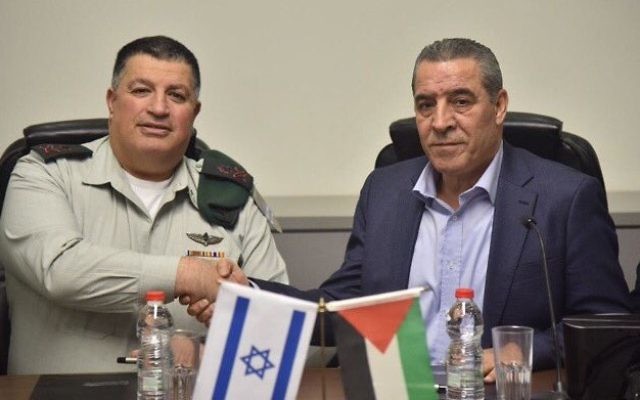 Le général de division Yoav Mordechaï, alors coordinateur des activités gouvernementales dans les territoires (COGAT), à gauche, et le ministre des Affaires civiles de l'Autorité palestinienne, Hussein al-Cheikh, signant un accord visant à revitaliser le comité mixte israélo-palestinien sur l'eau, le 15 janvier 2017. (Crédit : COGAT)