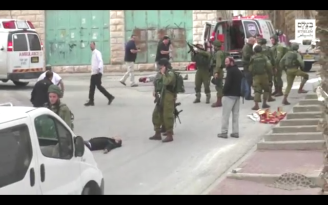 Un soldat israélien chargeant son arme avant de sembler tirer à la tête sur un assaillant palestinien au sol, apparemment désarmé, à la suite d'une attaque au couteau à Hébron, le 24 mars 2016. (Crédit : capture d'écran B'TSelem) Un soldat israélien chargeant son arme avant de sembler tirer à la tête sur un assaillant palestinien au sol, apparemment désarmé, à la suite d'une attaque au couteau à Hébron, le 24 mars 2016. (Crédit : capture d'écran B'TSelem)