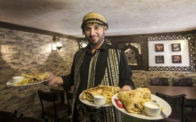 Anas Qaterji, un réfugié syrien qui a fui la guerre à Alep, en train de servir de la nourriture dans son restaurant dans le camp de réfugiés de Nuseirat, dans le centre de la bande de Gaza, le 3 janvier 2017 (Crédit : AFP PHOTO / MAHMUD HAMS)