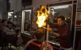 Ramadan Edwan, un coiffeur palestinien, utilise le feu pour coiffer ses clients, dans le camp de réfugiés de Rafah, dans le sud de la bande de Gaza, le 1er février 2017. (Crédit : Mahmud Hams/AFP)
