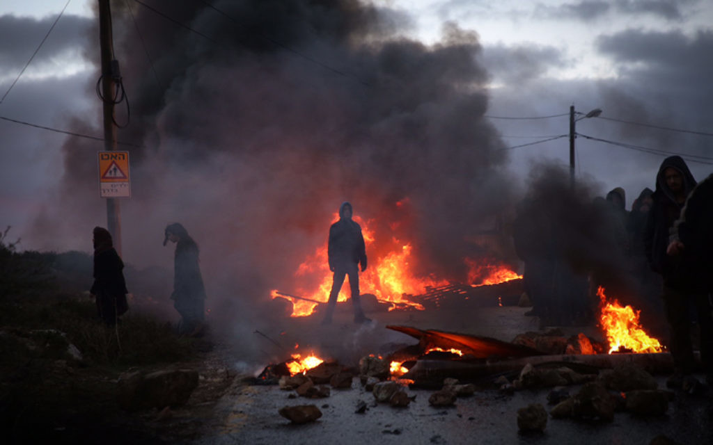 Des manifestants brûlent des pneus à l'entrée de l'avant-poste d'Amona, en Cisjordanie, le 1er février 2017. (Crédit : Hadas Parush/Flash90)