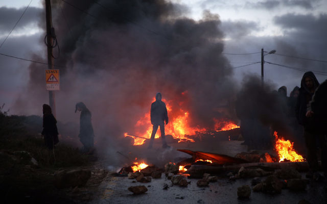 Des manifestants brûlent des pneus à l'entrée de l'avant-poste d'Amona, en Cisjordanie, le 1er février 2017. (Crédit : Hadas Parush/Flash90)