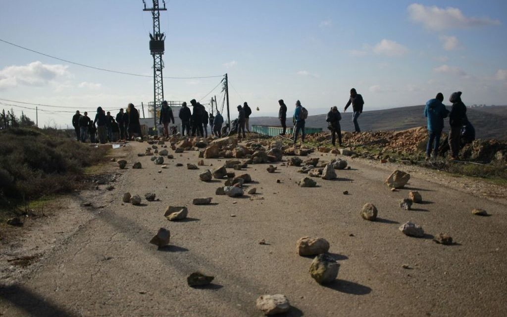 Des manifestants israéliens placent des rochers sur la route menant à l'avant-poste de Cisjordanie d'Amona, avant son démantèlement, le 1er février 2017. (Crédit : Judah Ari Gross/Times of Israël)