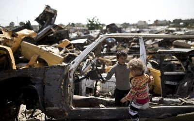 Des enfants palestiniens jouent dans des véhicules abandonnés dans une zone appauvrie dans la ville de Khan Yunis, dans le sud de la bande de Gaza, le 26 avril 2016 (Crédit : AFP / Mahmud Hams)