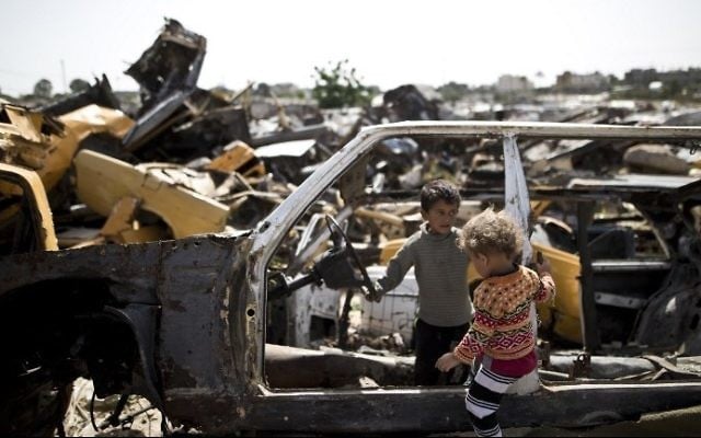 Des enfants palestiniens jouent dans des véhicules abandonnés dans une zone appauvrie dans la ville de Khan Yunis, dans le sud de la bande de Gaza, le 26 avril 2016 (Crédit : AFP / Mahmud Hams)