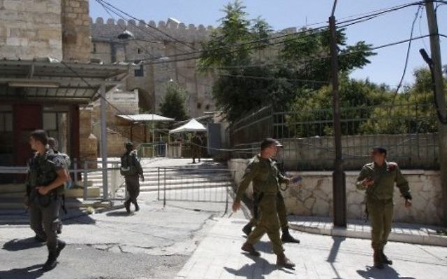 Forces de sécurité devant l'entrée du Tombeau des Patriarches, à Hébron, en Cisjordanie, le 1er juillet 2016. (Crédit : Hazem Bader/AFP)
