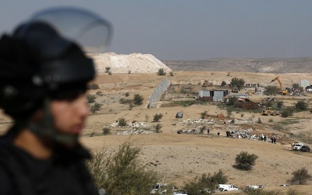 Un policier israélien en train de protéger les bulldozers qui détruisent des maisons dans le village bédouin d'Umm al-Hiran, dans le désert du Néguev, le 18 janvier 2017. (Crédit : Menahem Kahana/AFP) Un policier israélien en train de protéger les bulldozers qui détruisent des maisons dans le village bédouin d'Umm al-Hiran, dans le désert du Néguev, le 18 janvier 2017. (Crédit : Menahem Kahana/AFP)