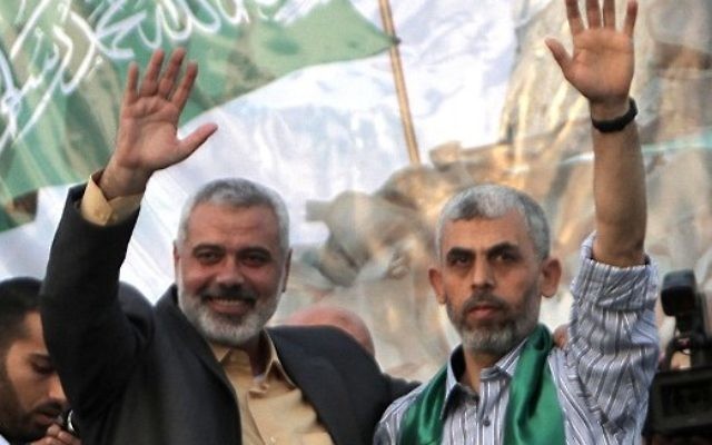Le dirigeant du Hamas de l'époque, Ismail Haniyeh (à gauche), et le prisonnier sécuritaire palestinien nouvellement libéré, Yahya Sinwar, saluent les supporters qui célèbrent la libération de 1 027 prisonniers de sécurité dans le cadre d'un échange contre le soldat de Tsahal enlevé, Gilad Shalit, à Khan Younès, dans le sud de la bande de Gaza, le 21 octobre 2011. (Crédit : Said Khatib/AFP)