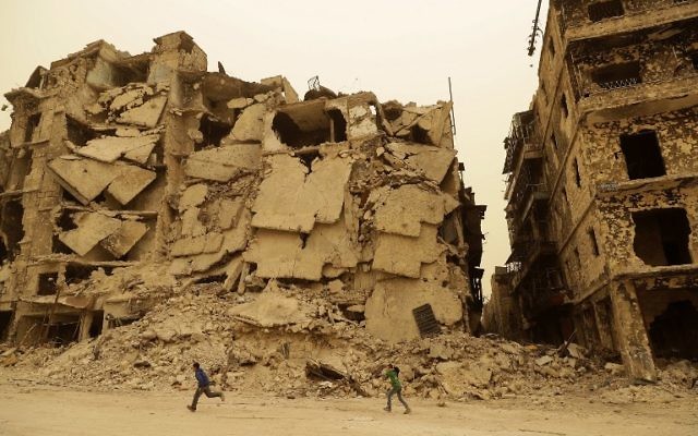 Des enfants syriens dans le quartier détruit de Kastal al-Harami à Alep, autrefois aux mains des rebelles, pendant une tempête de sable, le 10 mars 2017. (Crédit : Joseph Eid/AFP) Des enfants syriens dans le quartier détruit de Kastal al-Harami à Alep, autrefois aux mains des rebelles, pendant une tempête de sable, le 10 mars 2017. (Crédit : Joseph Eid/AFP)