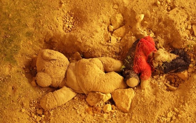 Un ours en peluche enterré dans le sol d'une maison du quartier de Bab Kinnisrin à Alep, autrefois aux mains des rebelles, pendant une tempête de sable, le 10 mars 2017. (Crédit : Joseph Eid/AFP)