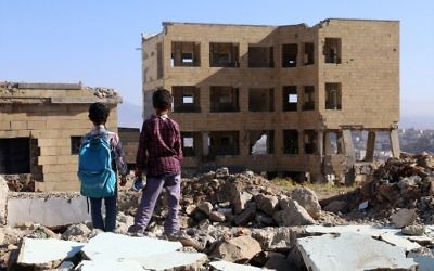 Des enfants yéménites devant une école détruite par une frappe aérienne dans la ville de Taëz, dans le sud du Yémen, le 16 mars 2017. (Crédit : Ahmad Al-Basha/AFP)