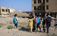 Des fillettes yéménites devant une école détruite par une frappe aérienne dans la ville de Taëz, dans le sud du Yémen, le 16 mars 2017. (Crédit : Ahmad Al-Basha/AFP)