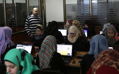 Des employées entrent des données dans les bureaux d'Unit One à Gaza (Crédit : Mahmud Hams / AFP)