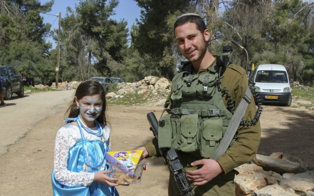 Un soldat israélien reçoit un cadeau d'une fillette à Shmurat Oz Vegaon, dans le Gush Etzion, pour la fête de Pourim, le 12 mars 2017. (Crédit : Gershon Elinson/Flash90)