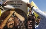 Un homme avec une photo du terroriste palestinien condamné Marwan Barghouthi pour demander sa libération pendant une manifestation de soutien aux détenus en grève de la faim à Hébron, en Cisjordanie, le 17 avril 2017. (Crédit : Hazem Bader/AFP)