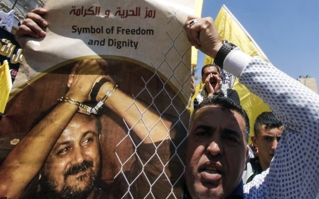 Un homme avec une photo du terroriste palestinien condamné Marwan Barghouthi pour demander sa libération pendant une manifestation de soutien aux détenus en grève de la faim à Hébron, en Cisjordanie, le 17 avril 2017. (Crédit : Hazem Bader/AFP) Un homme avec une photo du terroriste palestinien condamné Marwan Barghouthi pour demander sa libération pendant une manifestation de soutien aux détenus en grève de la faim à Hébron, en Cisjordanie, le 17 avril 2017. (Crédit : Hazem Bader/AFP)