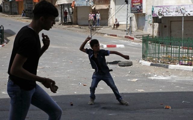 Illustration : Des manifestants palestiniens jettent des pierres sur des soldats israéliens à Hébron, en Cisjordanie, le 27 avril 2017.. (Crédit : Hazem Bader/AFP) Illustration : Des manifestants palestiniens jettent des pierres sur des soldats israéliens à Hébron, en Cisjordanie, le 27 avril 2017.. (Crédit : Hazem Bader/AFP)