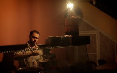 Un Palestinien utilise une lampe à gaz pour travailler dans son restaurant qui n'a plus d'électricité, dans la bande de Gaza, le 17 novembre 2013. (Crédit : Emad Nassar/Flash90)