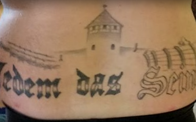 Le tatouage sur le dos d'un homme politique allemand de l'extrême droite, Marcel Zech, représentant le camp de la mort d'Auschwitz avec le slogan de la porte du camp de concentration de Buchenwald, "Jedem das Seine" - "à chacun son dû". (Crédit : Capture d'écran YouTube) Le tatouage sur le dos d'un homme politique allemand de l'extrême droite, Marcel Zech, représentant le camp de la mort d'Auschwitz avec le slogan de la porte du camp de concentration de Buchenwald, "Jedem das Seine" - "à chacun son dû". (Crédit : Capture d'écran YouTube)