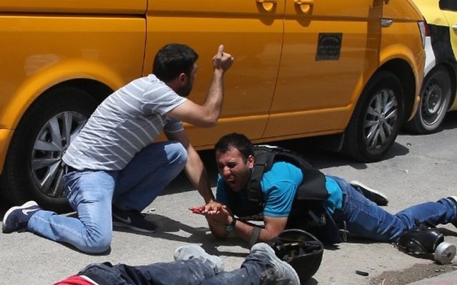 Un journaliste palestinien blessé près du corps d'un homme qui aurait été tué par un Israélien de Cisjordanie pendant des émeutes près d'Hawara, en Cisjordanie, le 18 mai 2017. (Crédit : Jaafar Ashtiyeh/AFP) Un journaliste palestinien blessé près du corps d'un homme qui aurait été tué par un Israélien de Cisjordanie pendant des émeutes près d'Hawara, en Cisjordanie, le 18 mai 2017. (Crédit : Jaafar Ashtiyeh/AFP)
