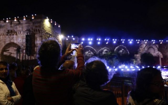 Les gens regardent la photo emblématique prise par David Rubinger de parachutistes israéliens le long du Mur occidental en Juin 1967 au cours d'un spectacle de son et lumière projeté sur les murs de la Vieille ville de Jérusalem pour célébrer le début de la semaine du 50ème anniversaire de la guerre israélo-arabe de 1967, le 20 mai 2017 (Crédit : GALI TIBBON / AFP PHOTO) Les gens regardent la photo emblématique prise par David Rubinger de parachutistes israéliens le long du Mur occidental en Juin 1967 au cours d'un spectacle de son et lumière projeté sur les murs de la Vieille ville de Jérusalem pour célébrer le début de la semaine du 50ème anniversaire de la guerre israélo-arabe de 1967, le 20 mai 2017 (Crédit : GALI TIBBON / AFP PHOTO)