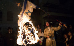 Un membre de la secte anti-sioniste Neturei Karta brûle un drapeau israélien pendant la fête de Lag BaOmer, dans le quartier ultra-orthodoxe de Mea Shearim, à Jérusalem, en mai 2014. (Crédit : Yonatan Sindel/Flash90)