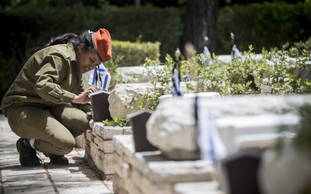 Une soldate israélienne allume des bougies près des tombes des soldats morts au combat au cimetière militaire du mont Herzl, à Jérusalem, le 30 avril 2017. (Crédit : Yonatan Sindel/Flash90) Une soldate israélienne allume des bougies près des tombes des soldats morts au combat au cimetière militaire du mont Herzl, à Jérusalem, le 30 avril 2017. (Crédit : Yonatan Sindel/Flash90)