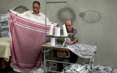Des Palestiniens travaillent dans une fabrique de Keffieh, à Hébron, en Cisjordanie, le 14 octobre 2010. (Crédit : Najeh Hashlamoun/Flash90)