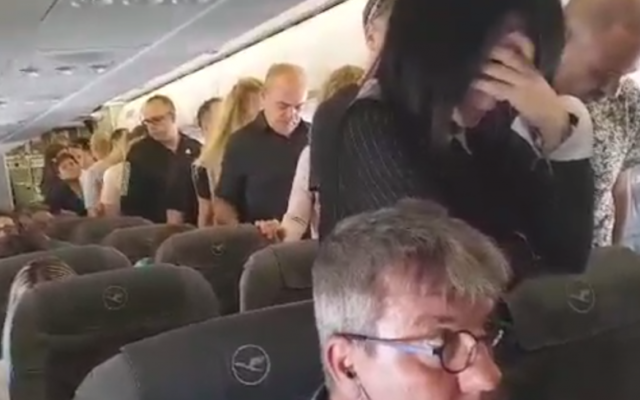 Un groupe d'Israéliens sur un vol de la Lufthansa se tiennent en silence dans le couloir au moment même où résonne en Israël la sirène qui ouvre Yom HaZikaron, le 1er mai 2017. (Crédit : capture d'écran YouTube) Un groupe d'Israéliens sur un vol de la Lufthansa se tiennent en silence dans le couloir au moment même où résonne en Israël la sirène qui ouvre Yom HaZikaron, le 1er mai 2017. (Crédit : capture d'écran YouTube)