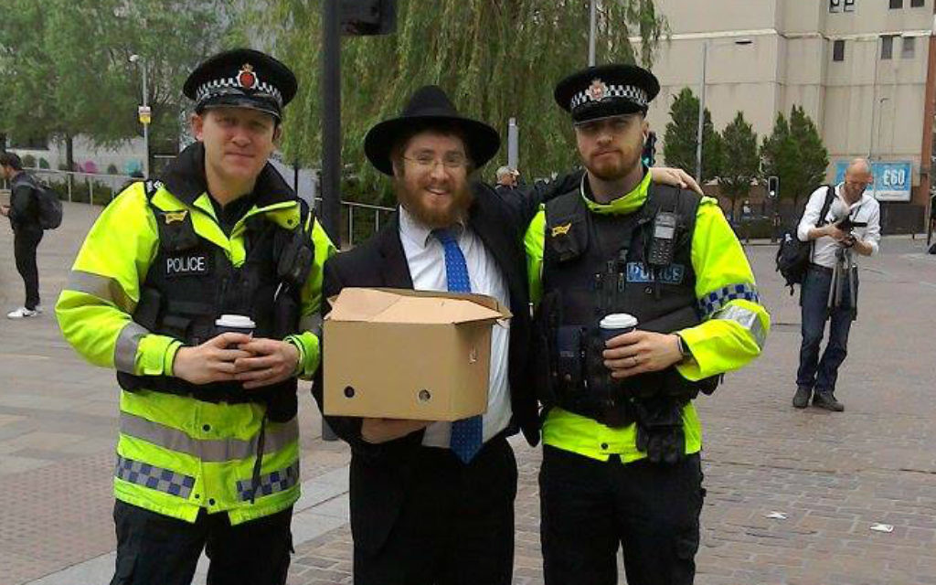 Le rabbin Shneur Cohen distribue des boissons chaudes et des viennoiseries à la police qui travaille sur les lieux de l'attentat qui a frappé Manchester, au Royaume-Uni, le 23 mai 2017. (Crédit : Chabad of Manchester City Center) Le rabbin Shneur Cohen distribue des boissons chaudes et des viennoiseries à la police qui travaille sur les lieux de l'attentat qui a frappé Manchester, au Royaume-Uni, le 23 mai 2017. (Crédit : Chabad of Manchester City Center)