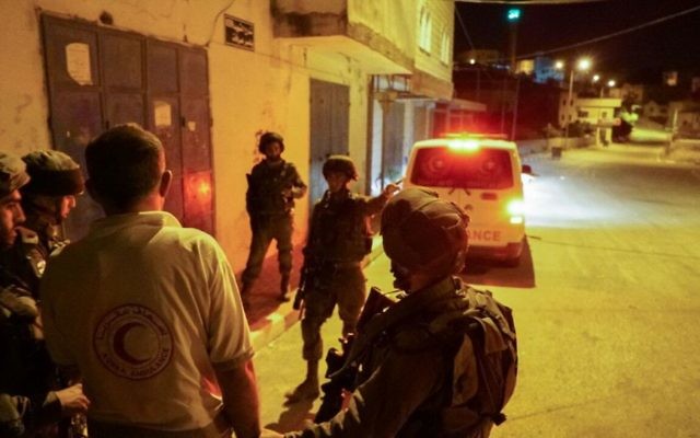 Des soldats arrêtent un conducteur d'ambulance, qui a empêché un véhicule israélien dans le nord de la Cisjordanie le 19 mai 2017. L'ambulance a bloqué la fuite d'un Israélien qui a été attaqué par une foule lors d'une manifestation dans le village de Hawara, en dehors de Naplouse. (Crédit : Unité des porte-paroles de l'armée israélienne)
