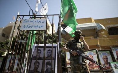 Un membre des Brigades Ezzedine al-Qassam, l'a branche armée du groupe terroriste du Hamas, à côté de fausses prisons lors d'un rassemblement marquant la Journée des prisonniers palestiniens dans la ville de Gaza, le 17 avril 2016. (Crédit : Mahmud Hams/AFP)